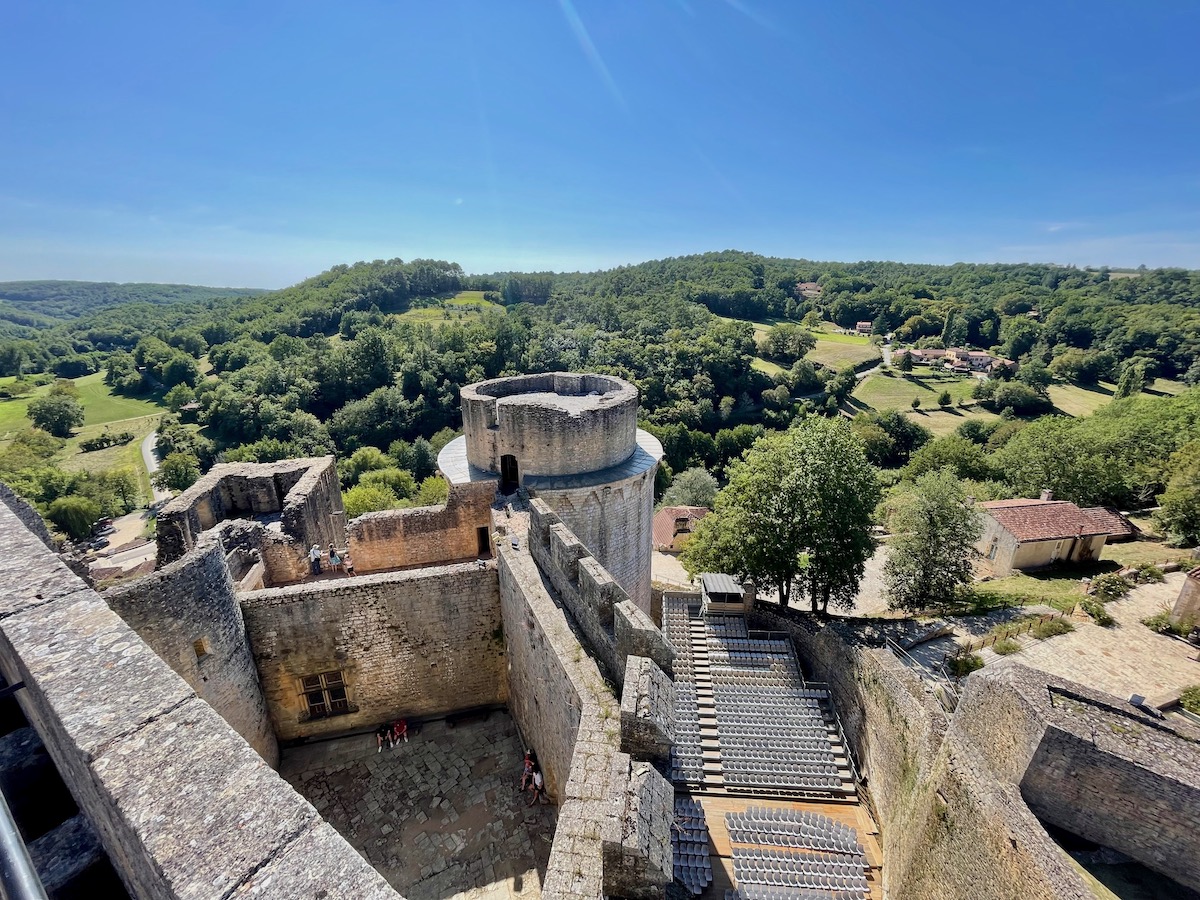 view of chateau de bonaguil and surrounding green countryside from the top of the tallest tower of the castle